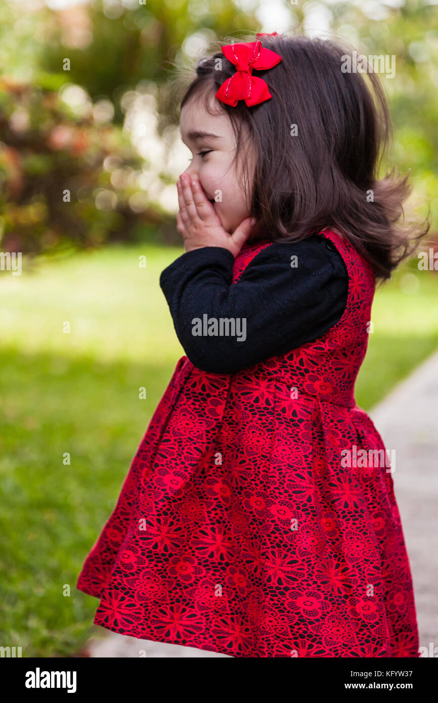 Shy, happy, smiling toddler baby girl giggling and laughing. Covering and hiding mouth and face to hide giggle, laugh or smile. Ten months old Stock Photo