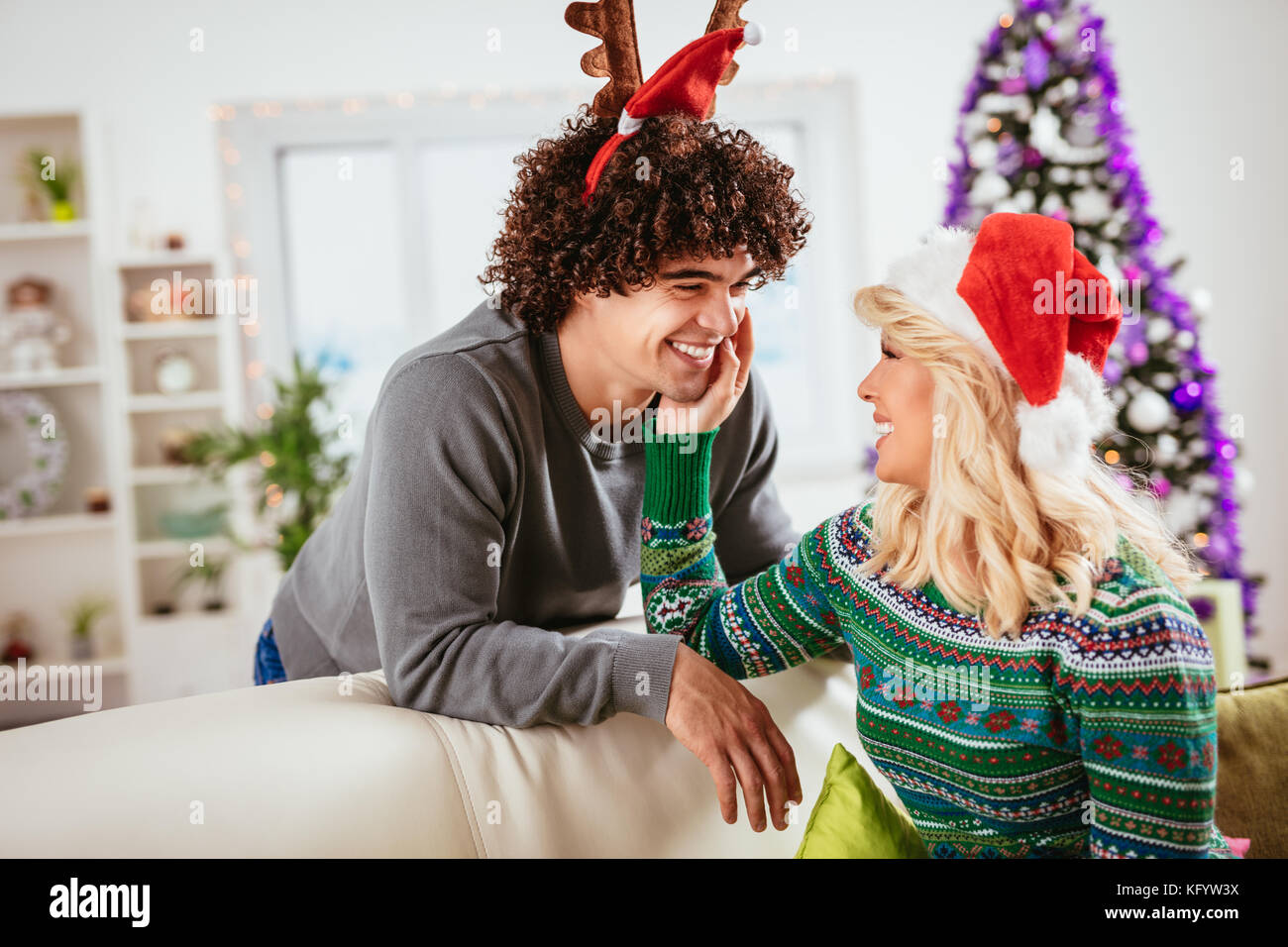 Loving couple in cozy warm sweaters on a Christmas New Year eve, smiling and having fun with each other. Stock Photo