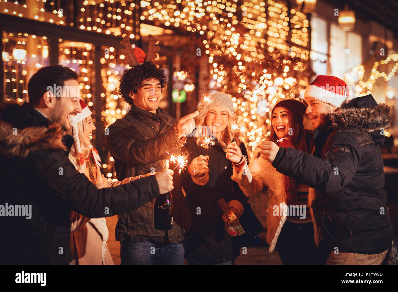 Group of happy friends having fun with sparklers on night Christmas party. Stock Photo