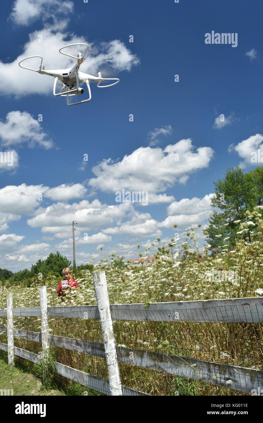 Teen boy flying DJI Phantom 4 Pro+ Drone to check fencing on rural farm in USA. Stock Photo