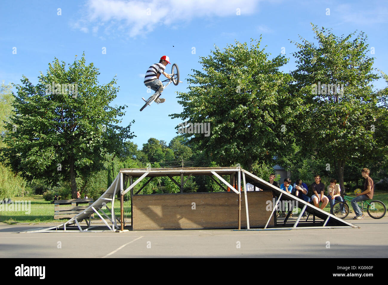 Teenagers execute bicycle tricks in a park Stock Photo