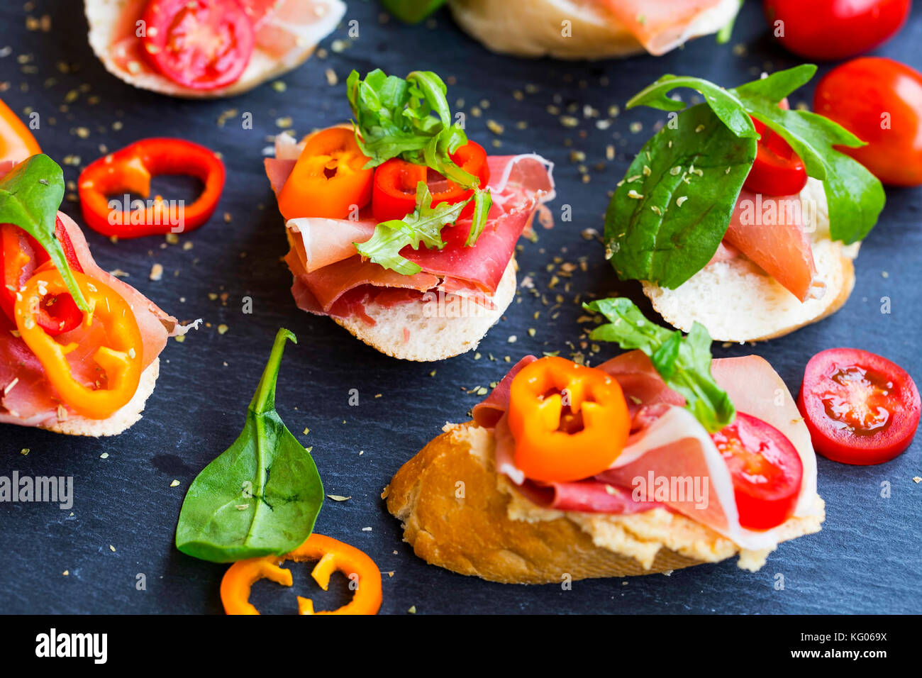 Canapes appetizer with prosciutto ham, pepper slices, tomatoes and