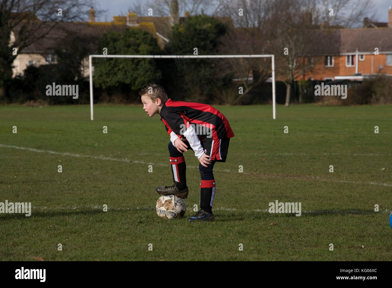 A boy wearing an AFC Bournemouth replica kit rests during a soccer training session. Stock Photo