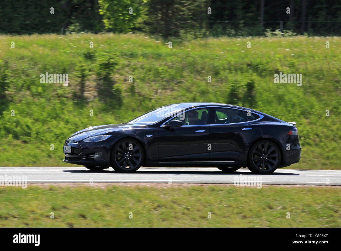 SALO, FINLAND - JUNE 3, 2016: Black Tesla Model S fully electric car at speed on the road at summer. In-camera panning effect. Stock Photo