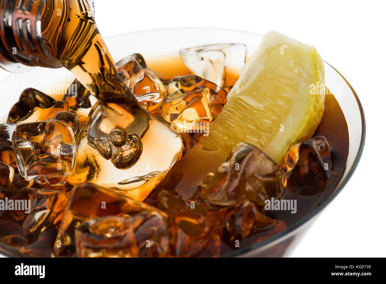 pouring cola into glass with ice cubes and lemon slice, on white background Stock Photo