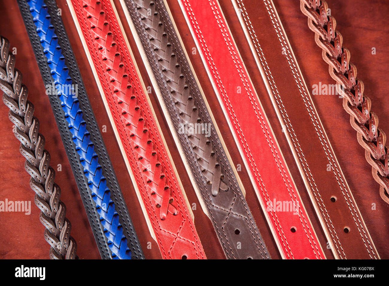 A close-up of narrow belts made of genuine red, blue and brown leather. Pattern made of leather belts Stock Photo