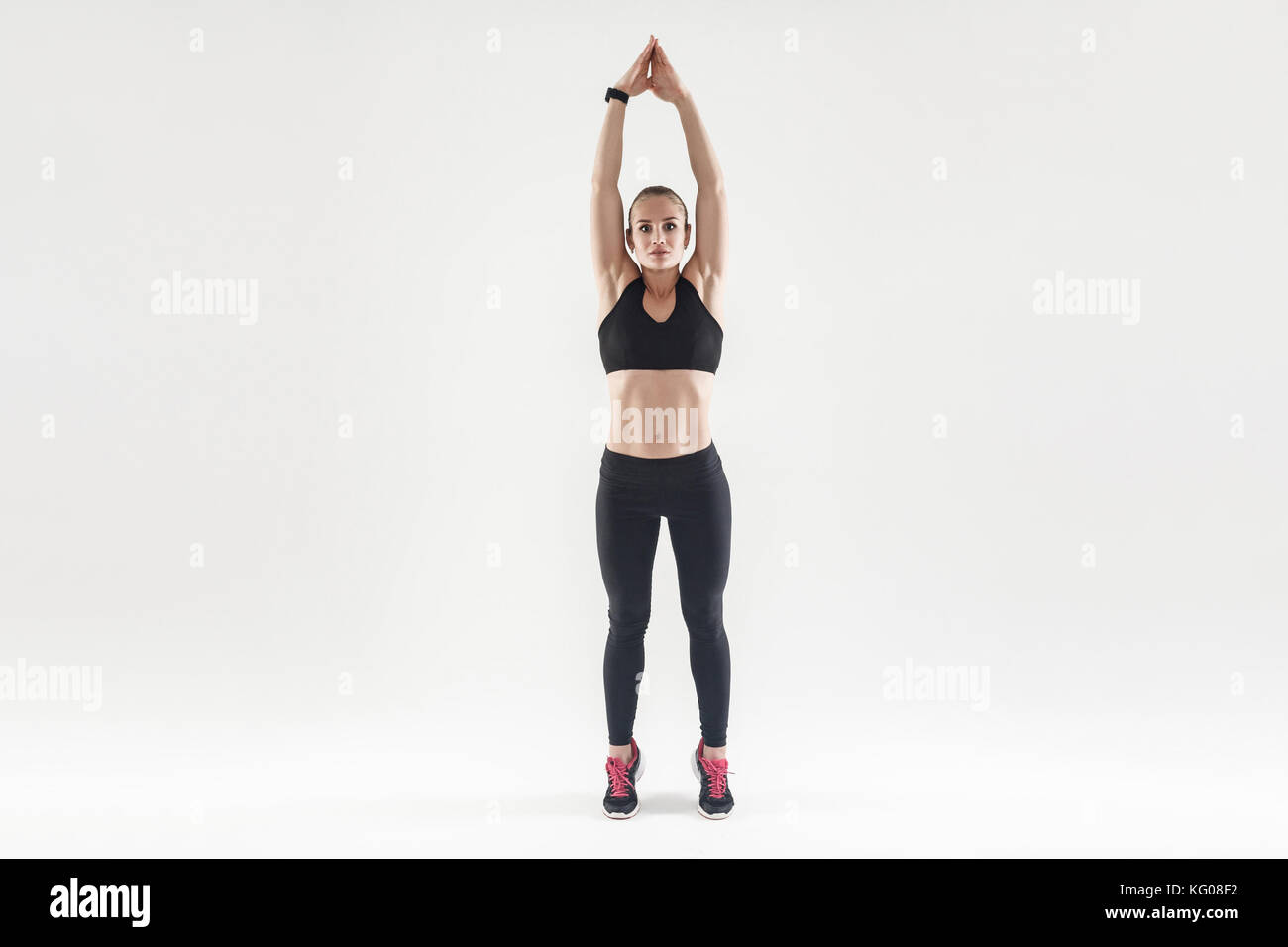 Easy aerobic exercising. Hands up and toe standing. Beautiful blonde woman. Studio shot, isolated on gray background Stock Photo