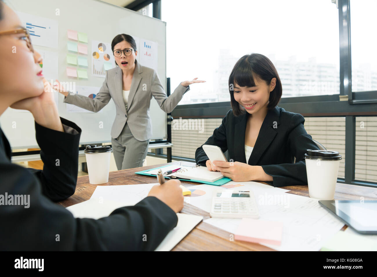 pretty young company female business manager looking at employees feeling angry when she finding they don't joining  meeting report. Stock Photo