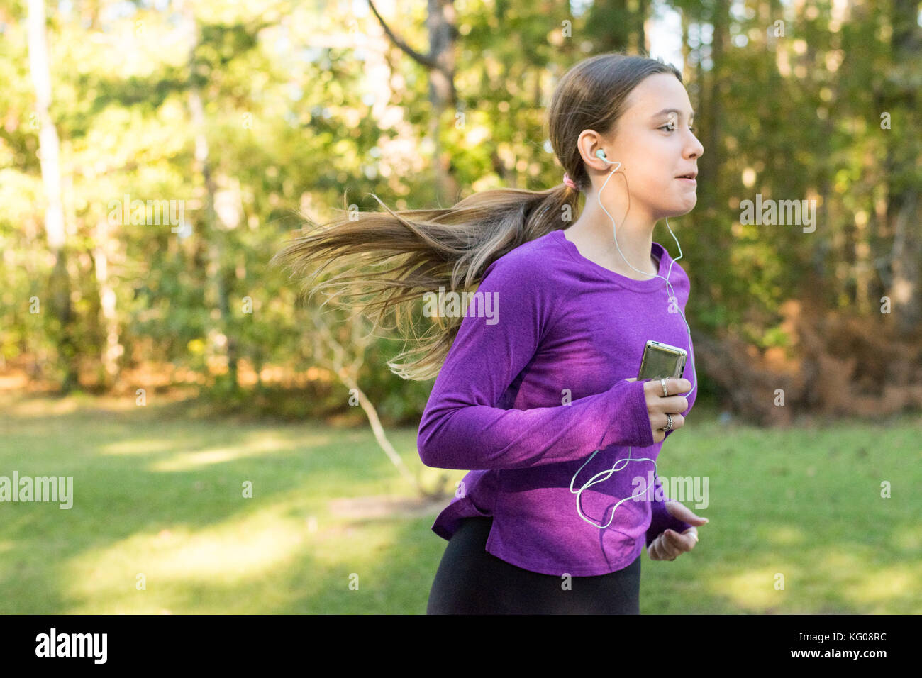 Teenage girl wearing purple running with ipod Stock Photo