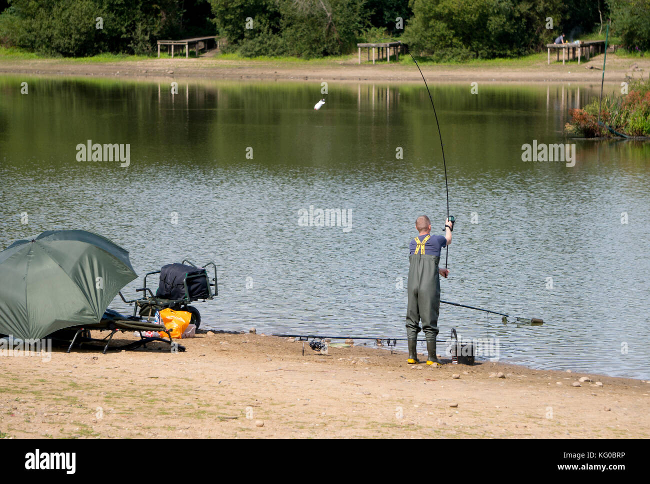 Angler casting his rod on the shore of a lake Stock Photo