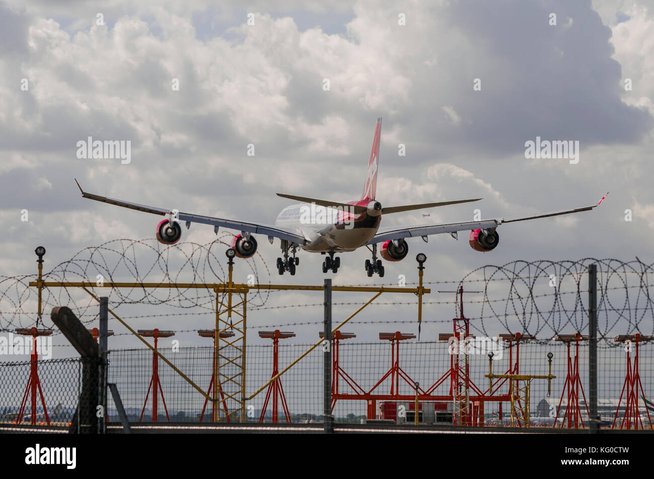 LONDON, UK - AUGUST, 3 2013; A Virgin Atlantic Airbus A340 landing at Heathrow airport in London, UK over the airport security fences. Stock Photo