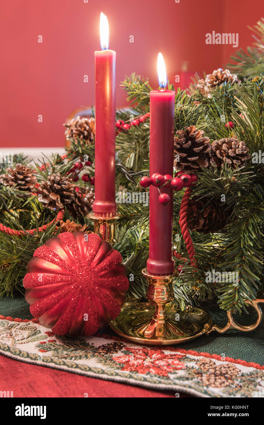 Christmas display with brass candlesticks, greenery, pine cones, and a red  ball ornament Stock Photo - Alamy