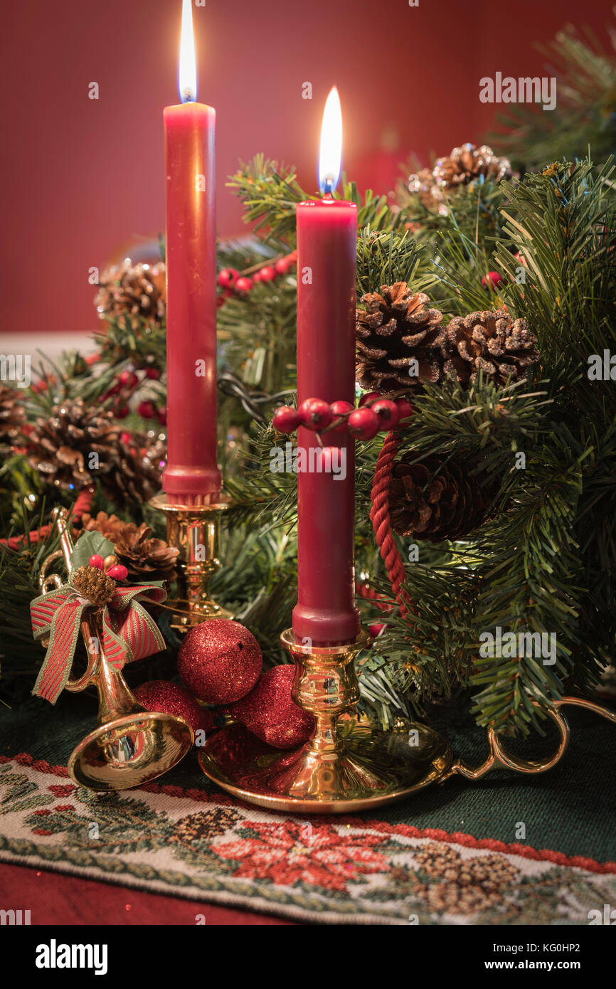 Christmas display with brass candlesticks, greenery, pine cones, and a golden horn ornament Stock Photo