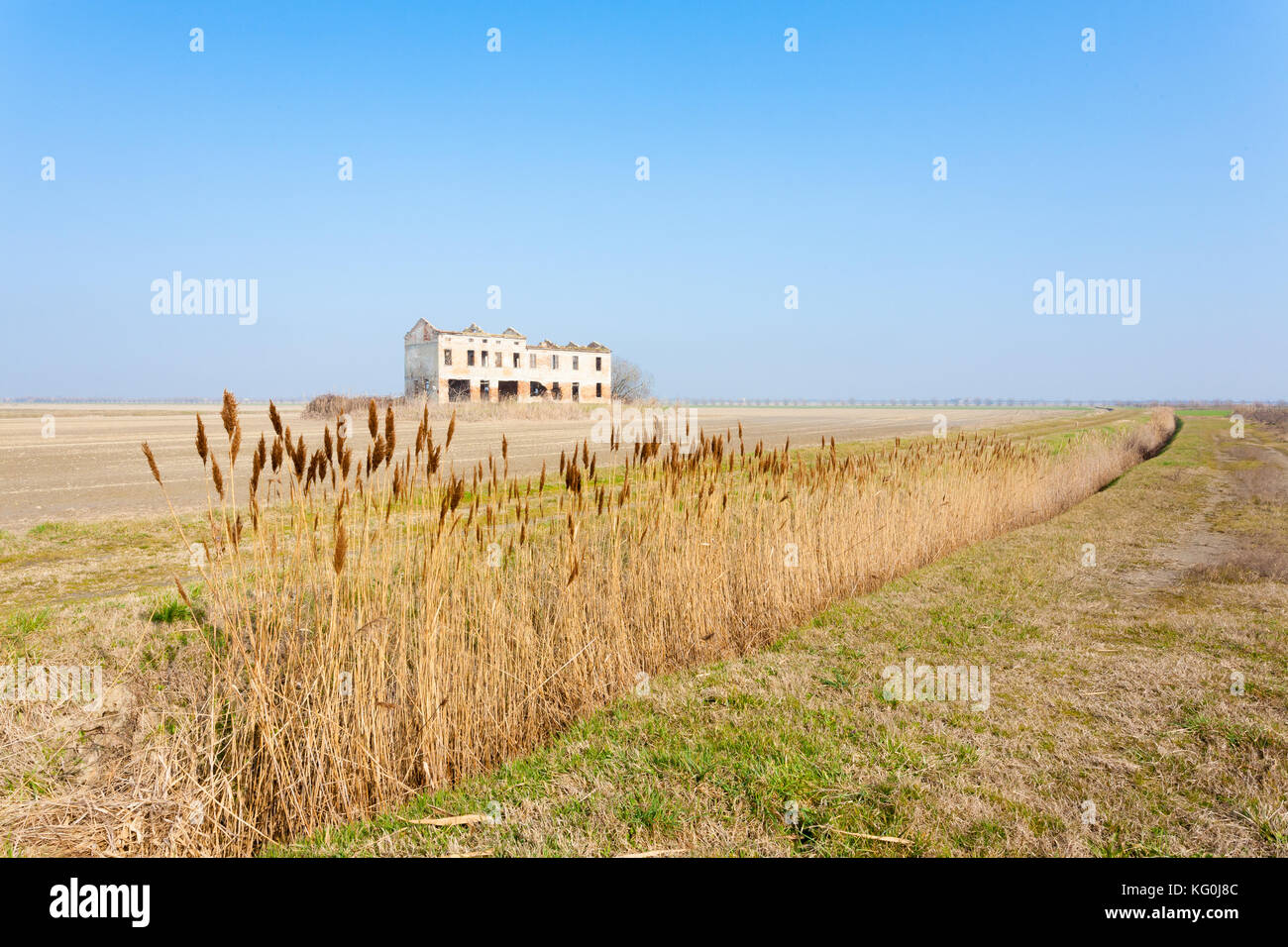 Rural Italian landscape from Po river lagoon.Plowed fields with perspective lines. Abandoned warehouse Stock Photo