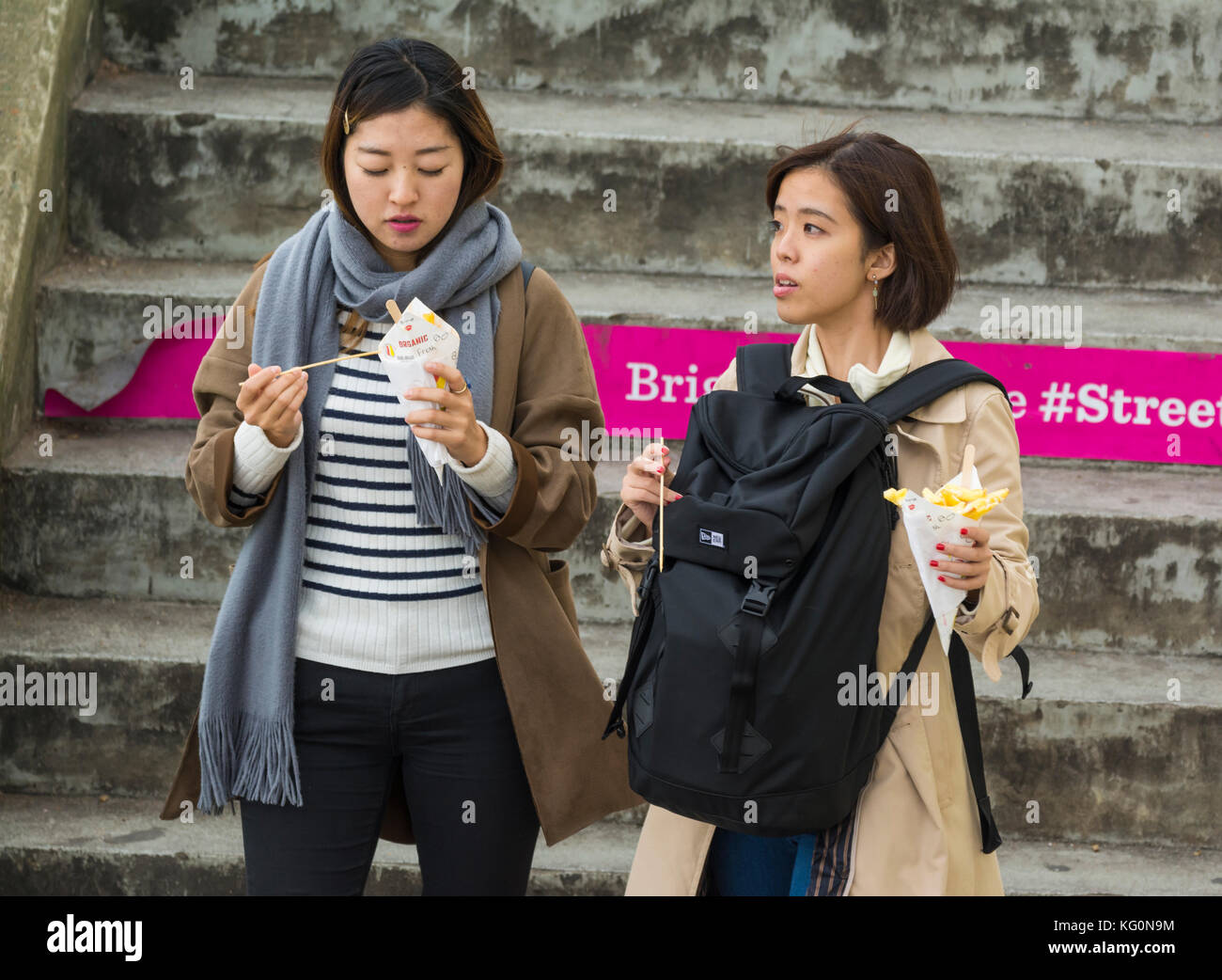 Young Asian women eating fish and chips takeaway in Brighton, East Sussex, England, UK. Stock Photo