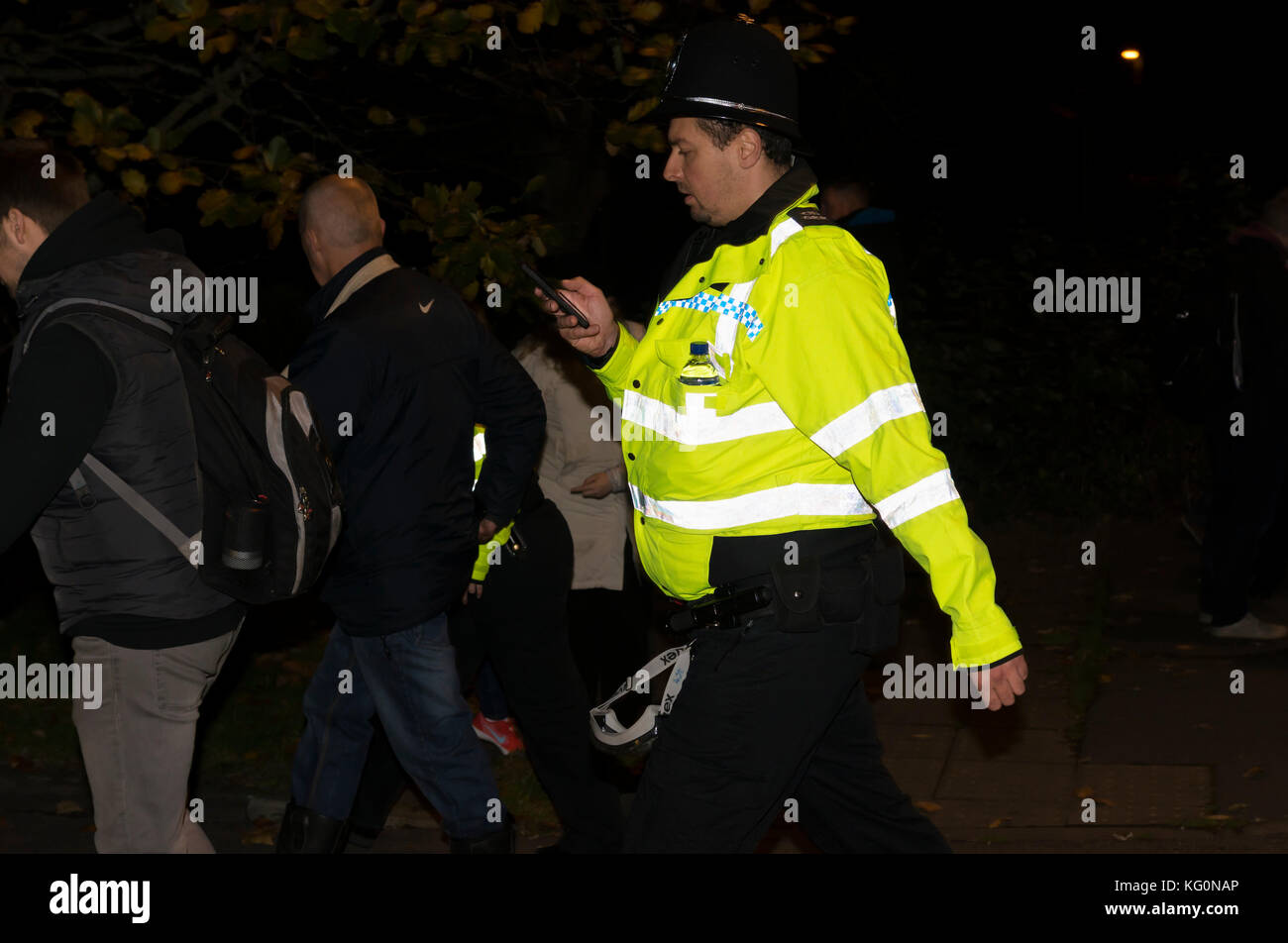 Policeman walking at a night time event in the UK. Stock Photo