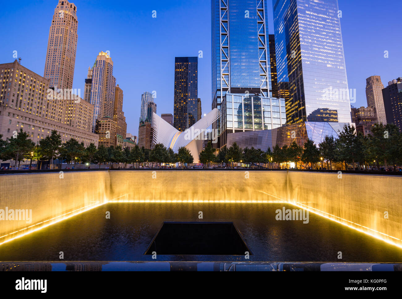 The North Reflecting Pool illuminated at twilight with view of the World Trade Center Tower 3 and 4. Lower Manhattan, 9/11 Memorial & Museum, New York Stock Photo