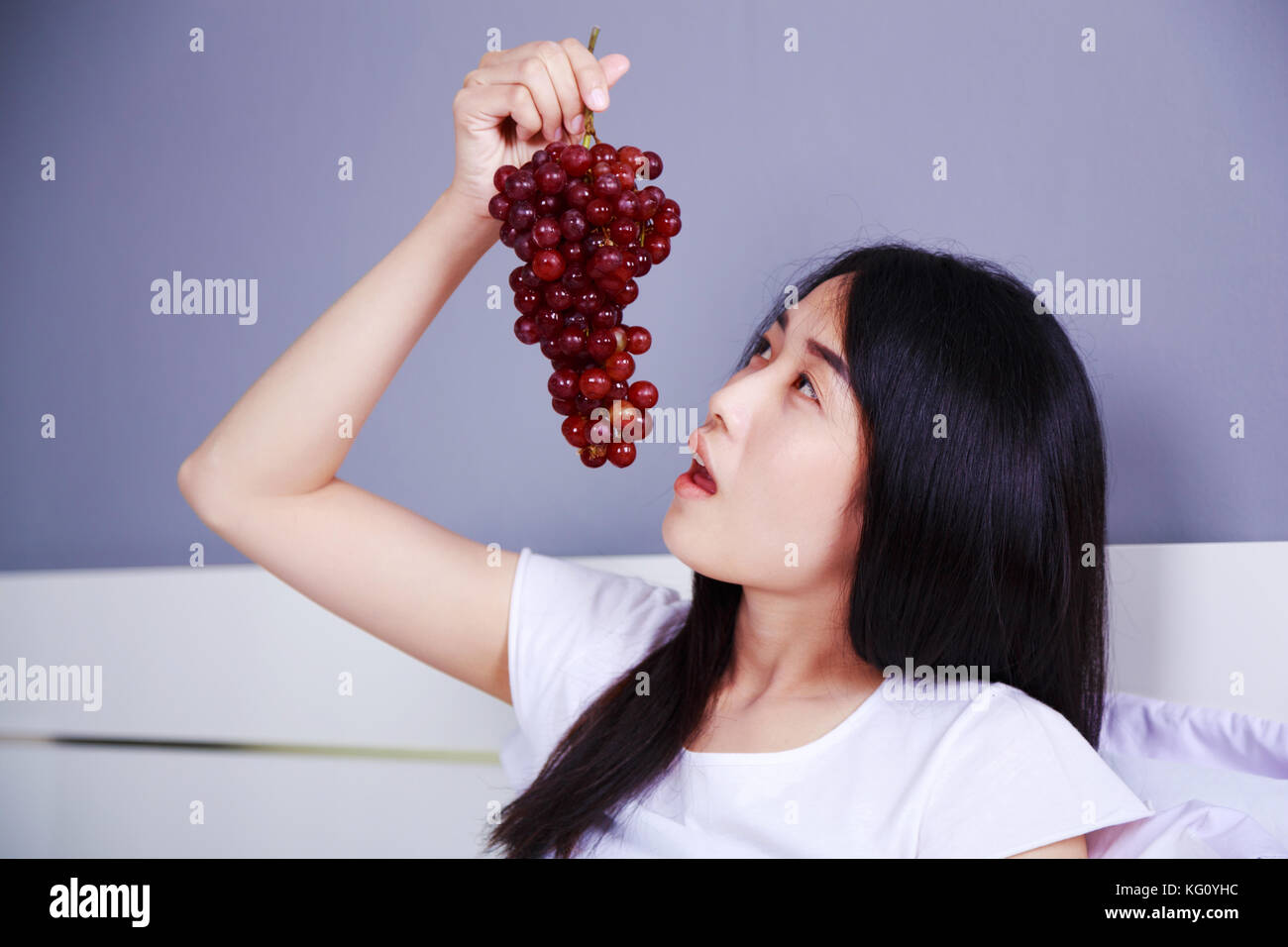 woman with red grape on bed in the bedroom Stock Photo Alamy
