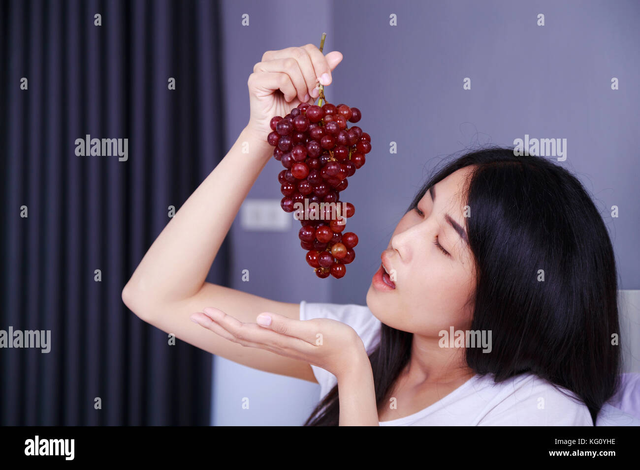 woman with red grape on bed in the bedroom Stock Photo Alamy