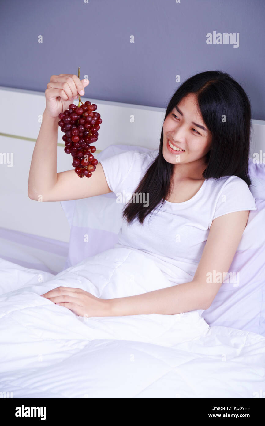 woman with red grape on bed in the bedroom Stock Photo Alamy