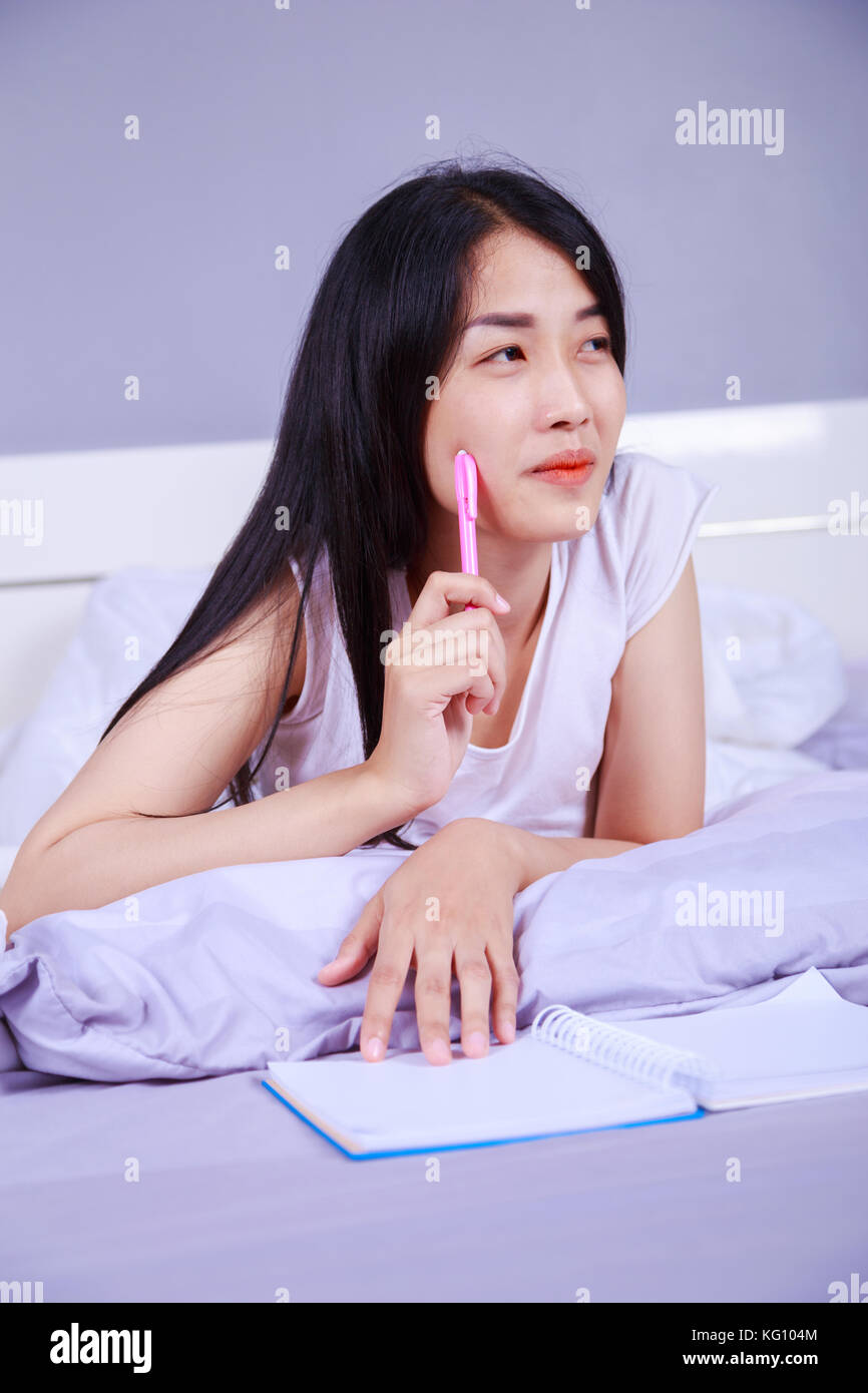 woman thinking and writing a book on her bed in the bedroom Stock Photo ...