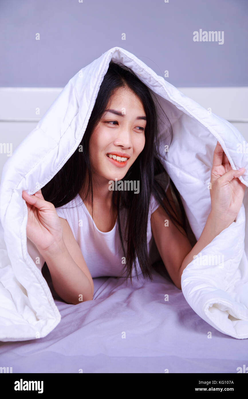 happy woman hiding under blanket on bed in the bedroom Stock Photo Alamy