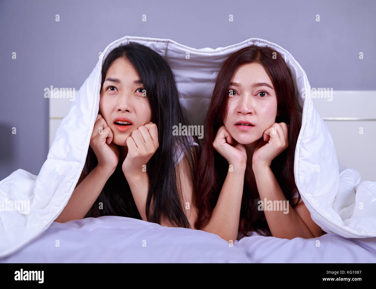 two best friend woman on bed watching a tv with shocked expression on face Stock Photo