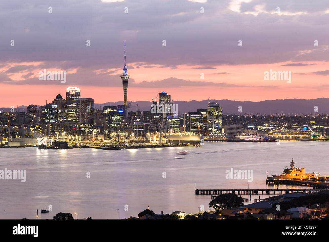 Sunset over Auckland central business district skyline and the harbor taken from the Davenport hill viewpoint in New Zealand largest city. Stock Photo
