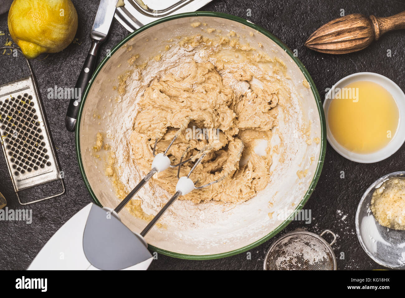 Mixing dough with hand mixer on kitchen table background with cooking ingredients, top view Stock Photo