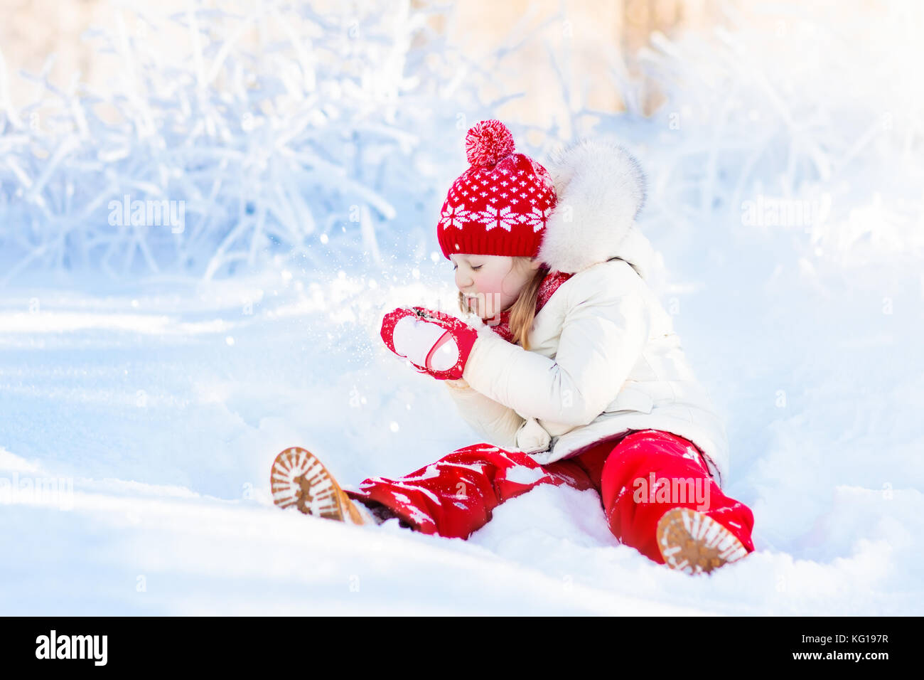 Child playing with snow in winter. Little girl in colorful jacket and ...