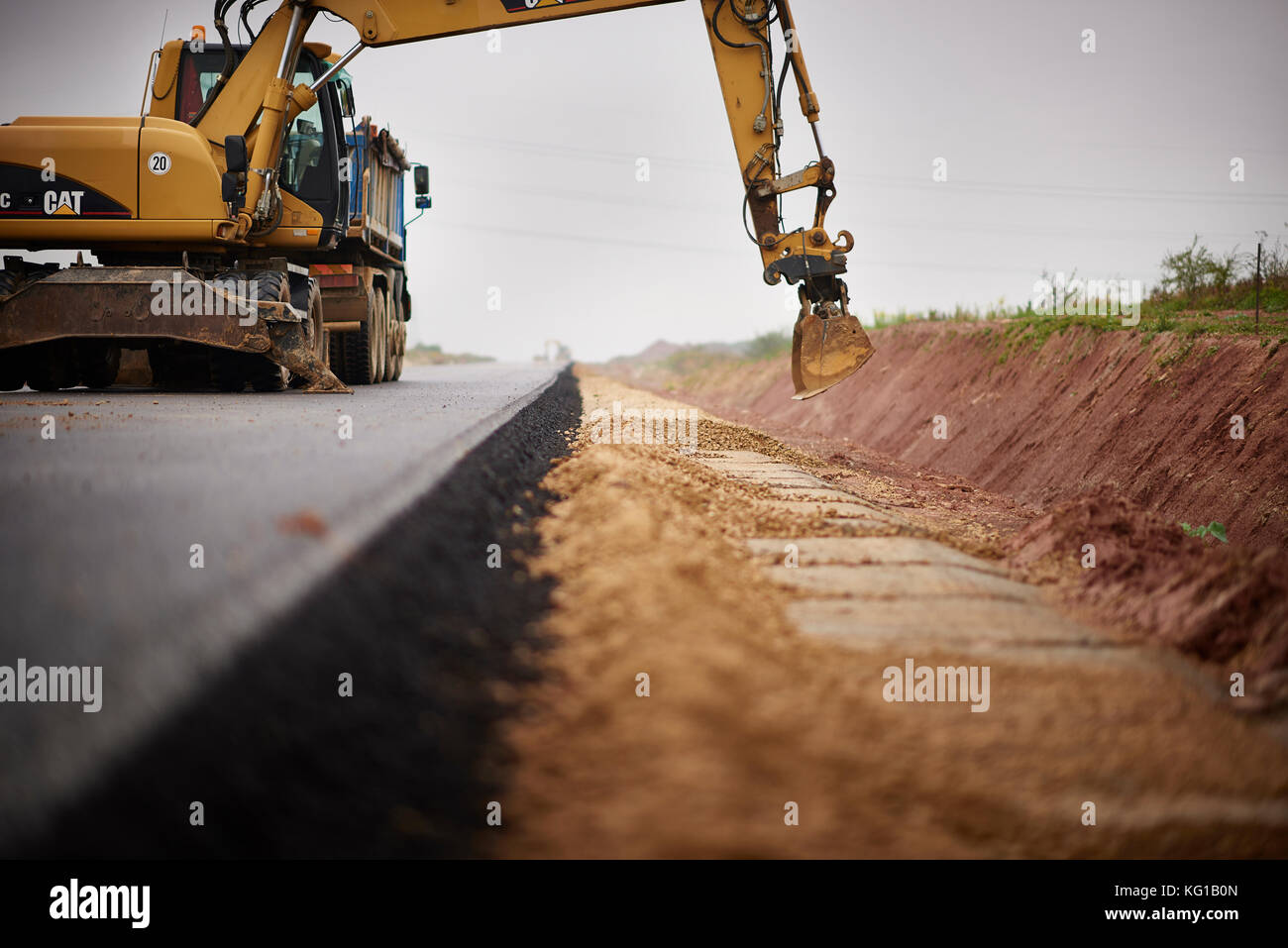 Road construction, asphalt paving, roadside hardening, excavator working on road construction Stock Photo