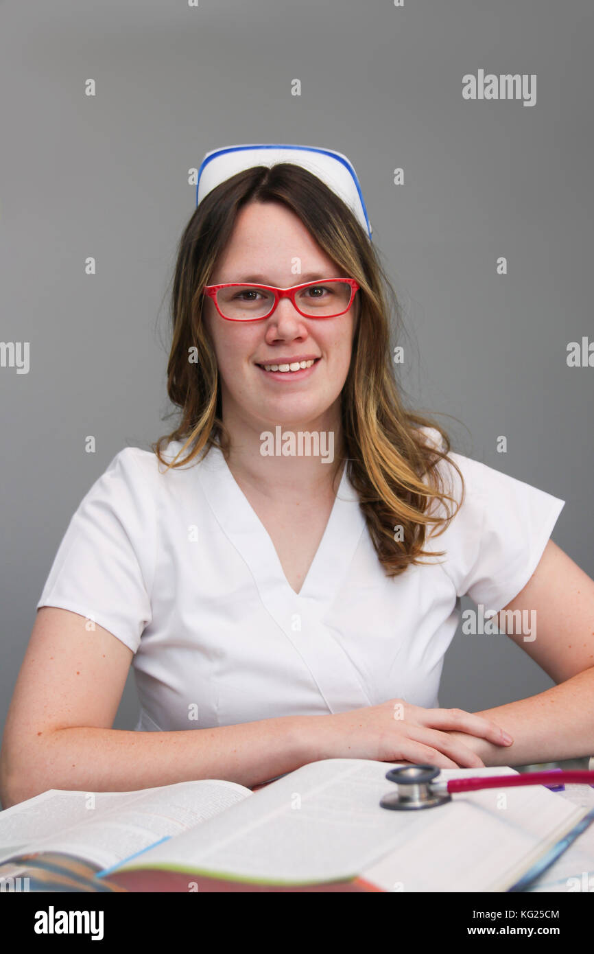 Young female nurse portrait wearing white scrubs, cap with nursing