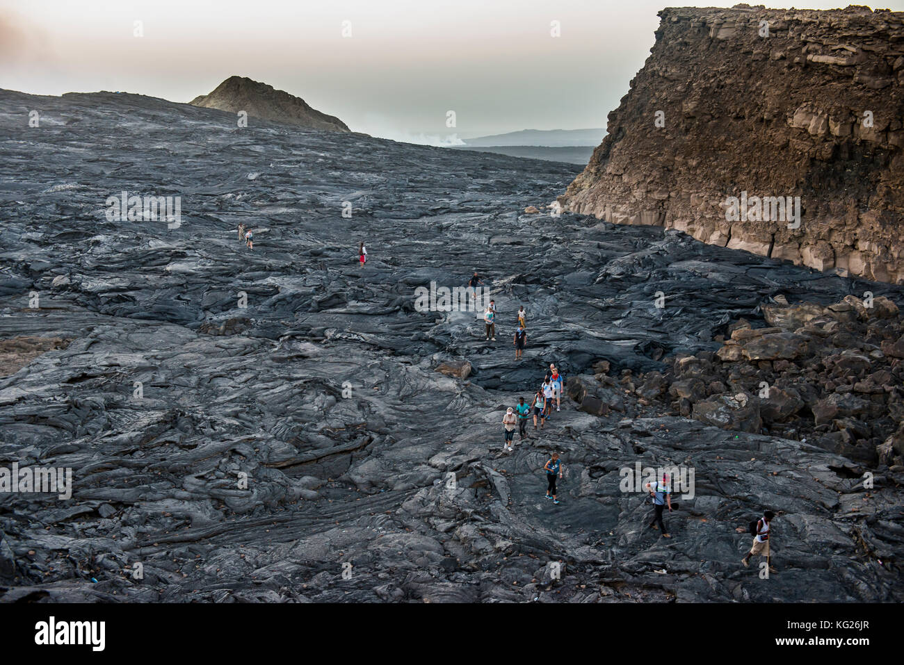 Tourists walking through lava field around the very active Erta Ale shield volcano, Danakil depression, Ethiopia, Africa Stock Photo