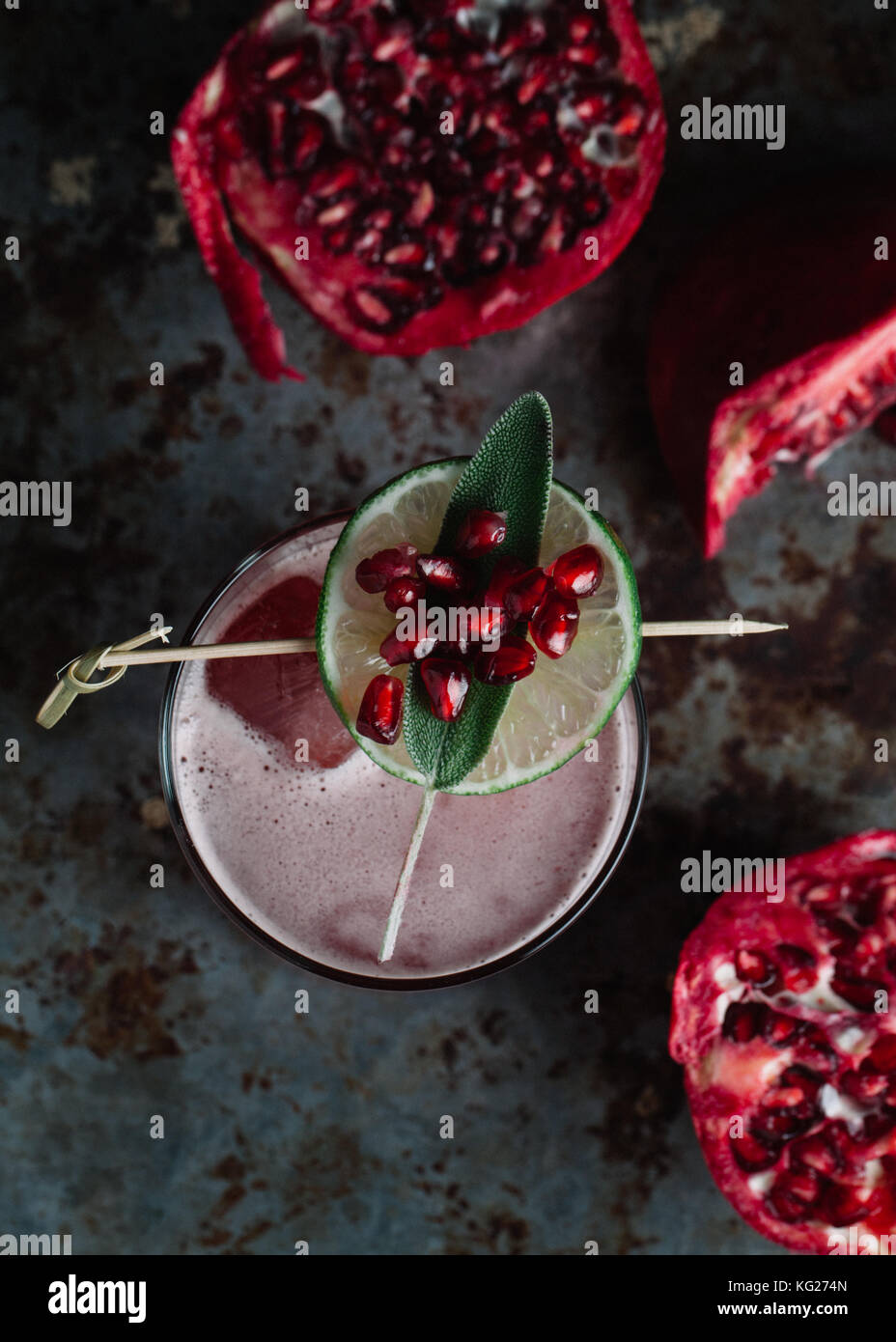Alcoholic cocktail garnished with pomegranate seeds on dark moody background Stock Photo