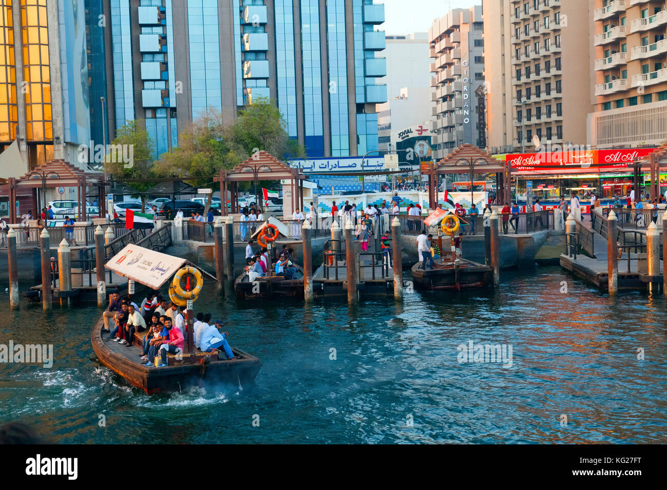 A water taxi carrying passengers arrives at a busy dock, Dubai Creek, Dubai, United Arab Emirates, Middle East Stock Photo