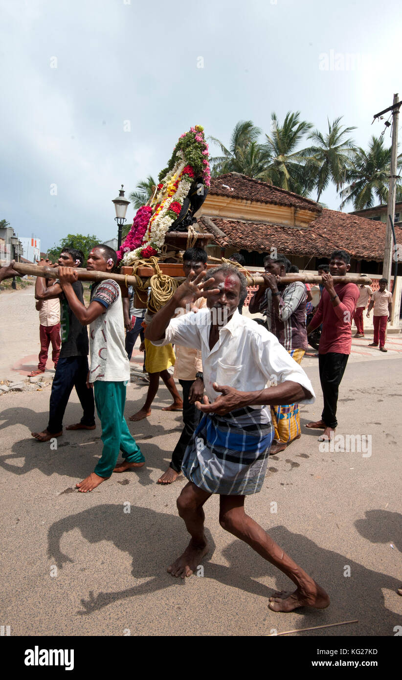 Men dancing to drumbeat as bronze deity covered with puja mala (garlands) being carried along the street, Tranquebar, Tamil Nadu, India, Asia Stock Photo