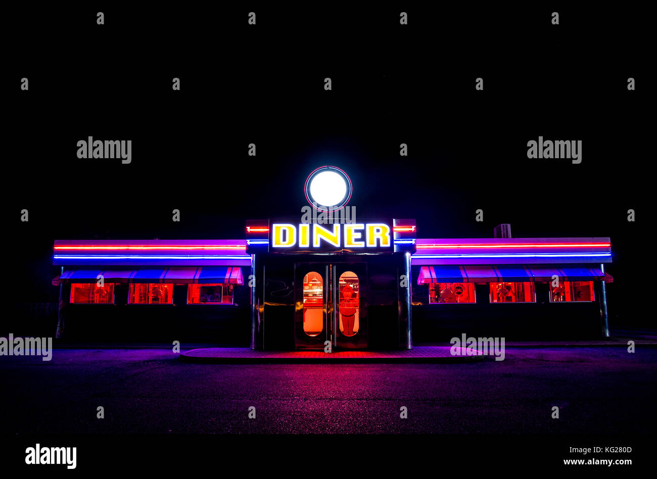 A traditional American Diner at night with a large sign and colourl luminous, fluourescent and neon lighting that glows in the dark. Stock Photo