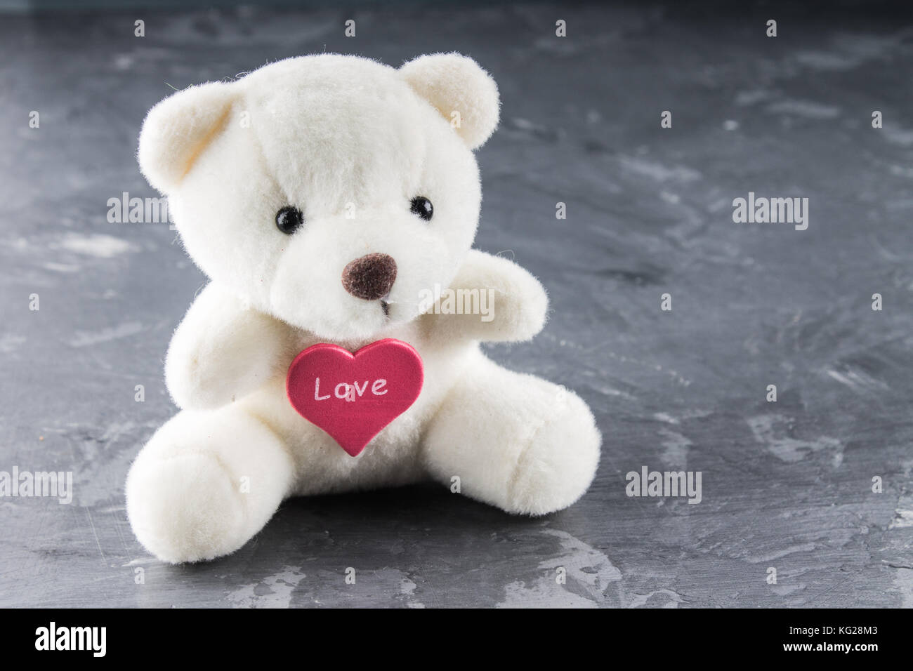 White teddy bear with love letter on red heart on gray background. Say ...