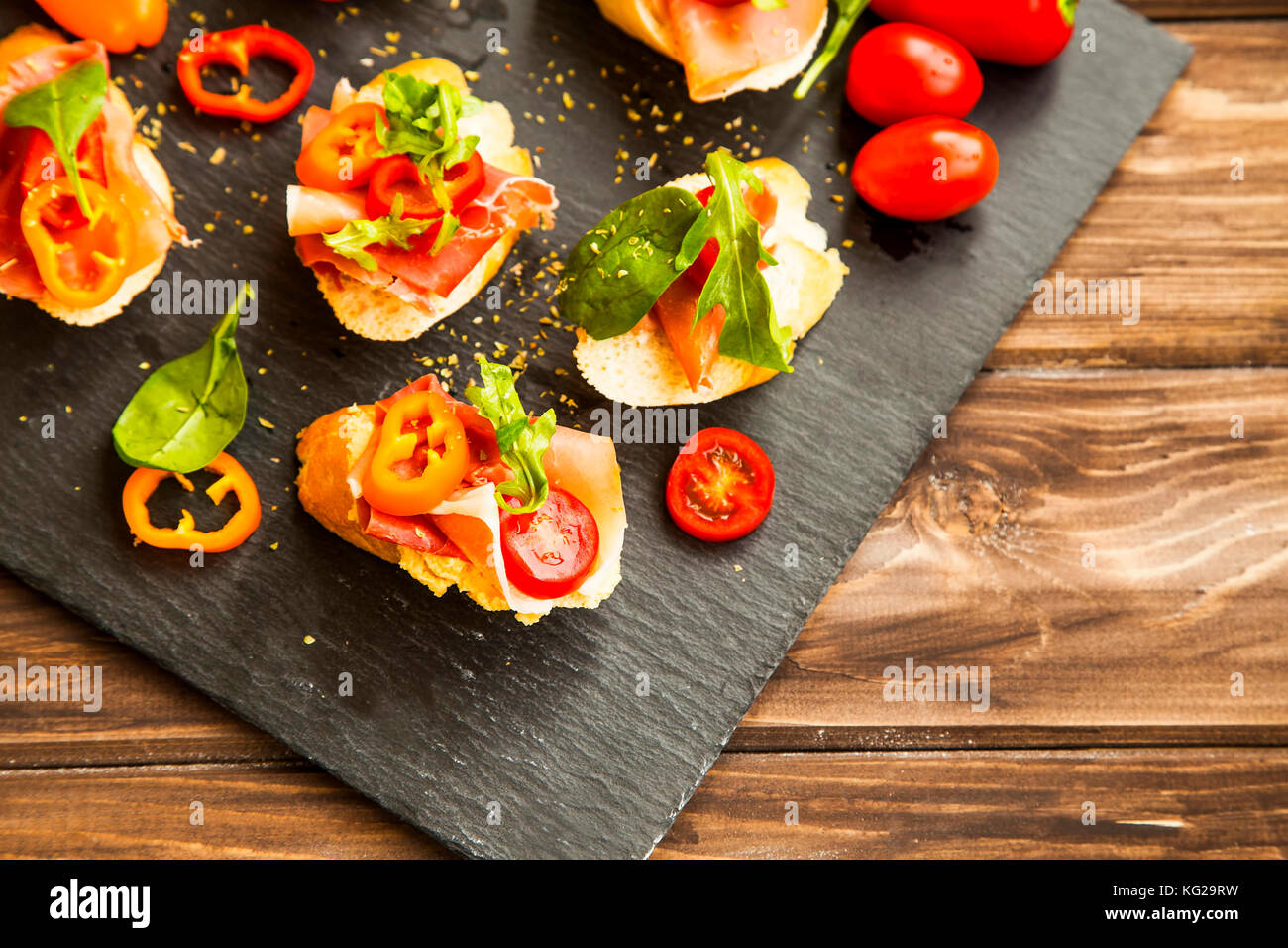Canapes appetizer with prosciutto ham, pepper slices, tomatoes and