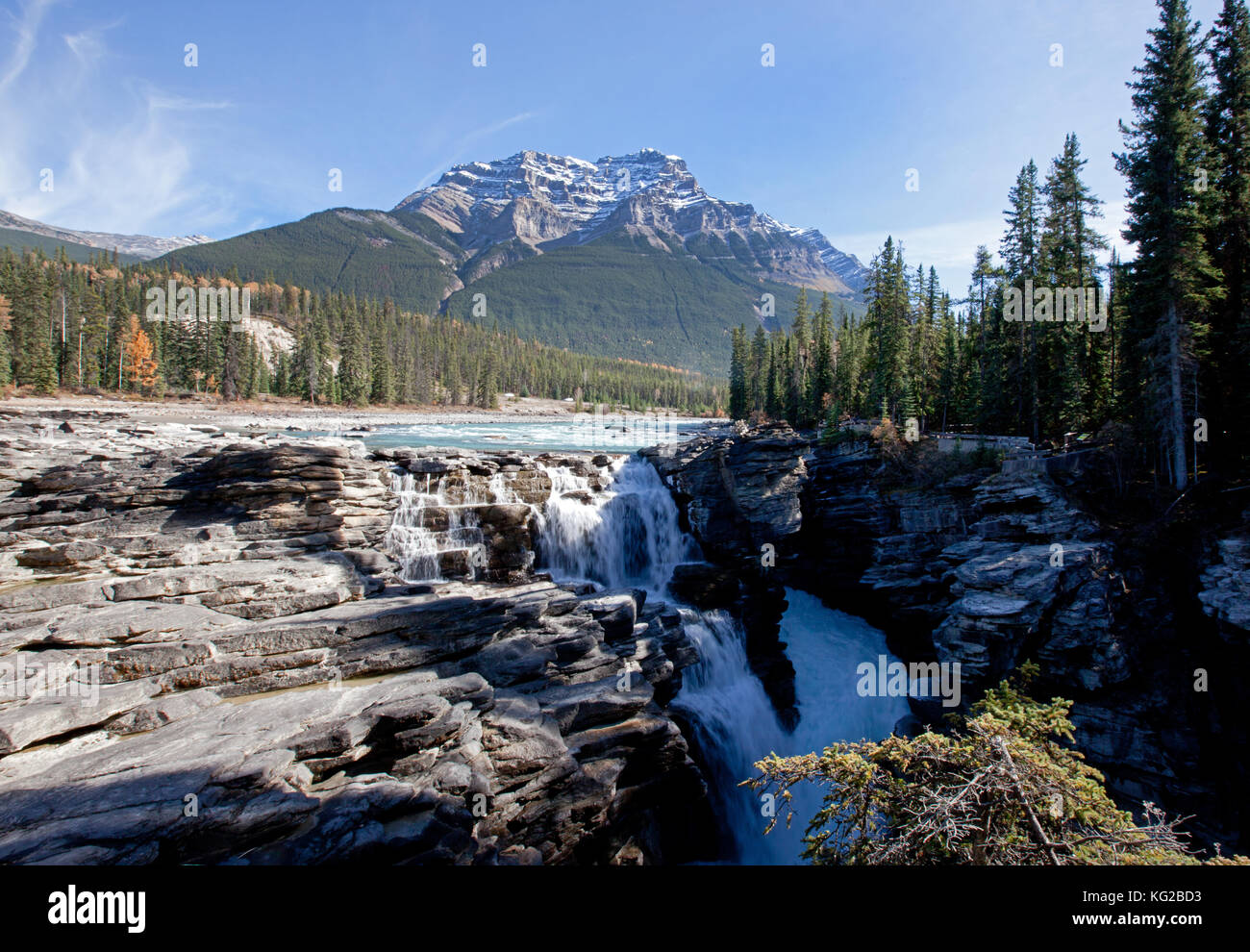 water rushes over the rocks with mountain behind in jasper, alberta ...