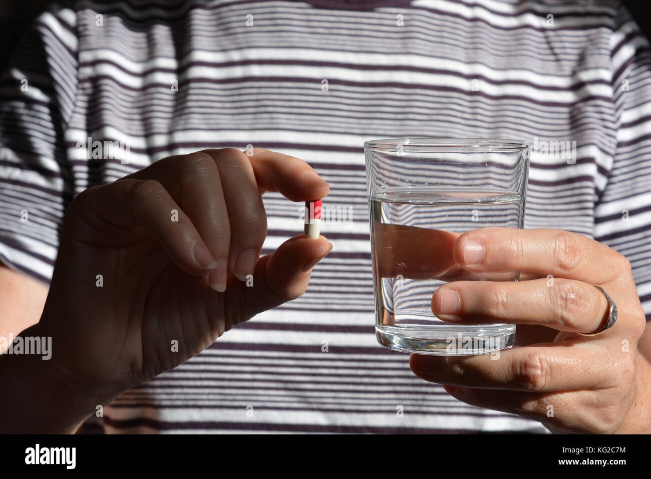Healthcare & Medicines. Woman holding a gel capsule and a glass of