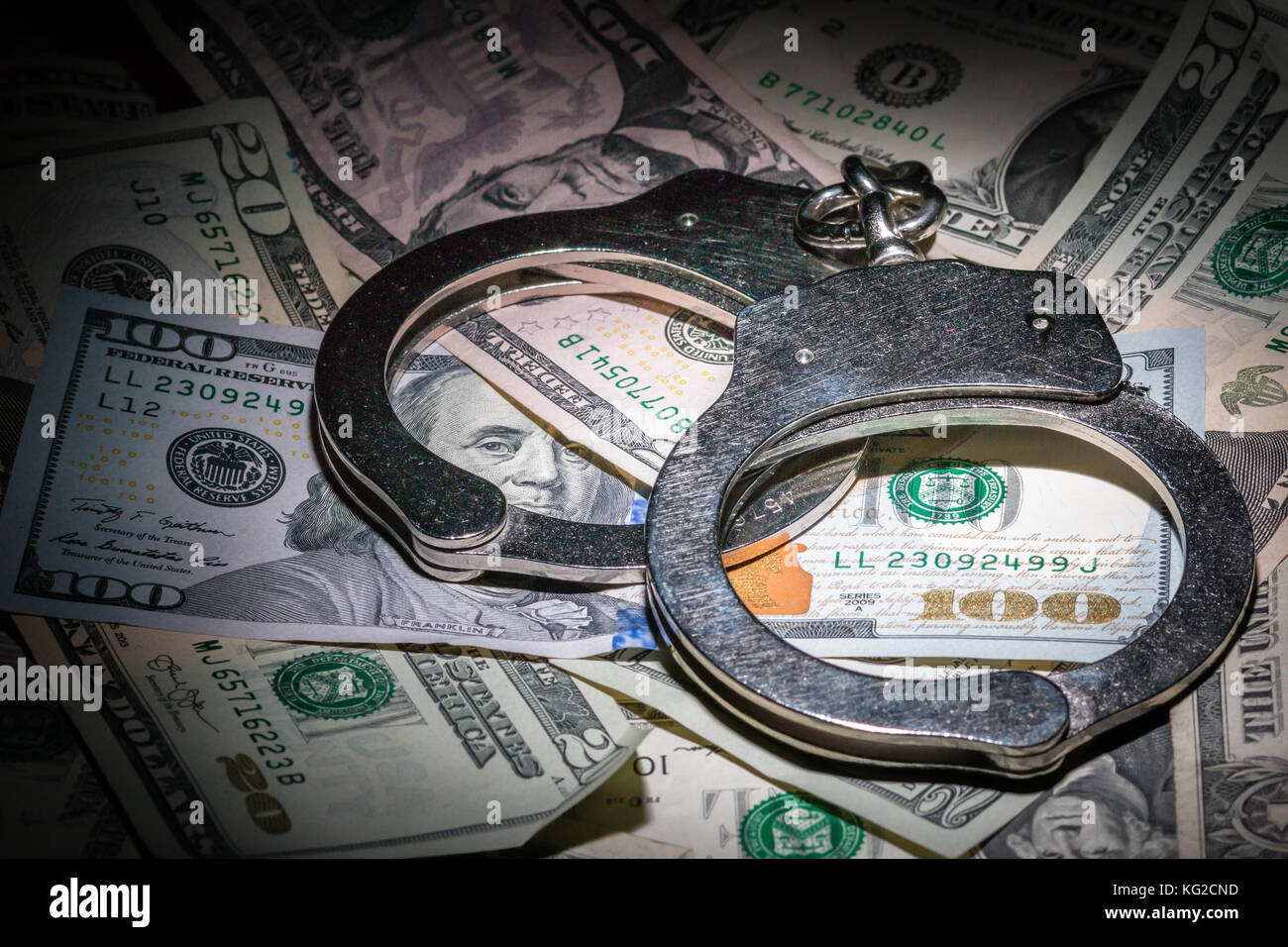 A pair of closed handcuffs on a pile of American Dollars with a deep depth of field Stock Photo
