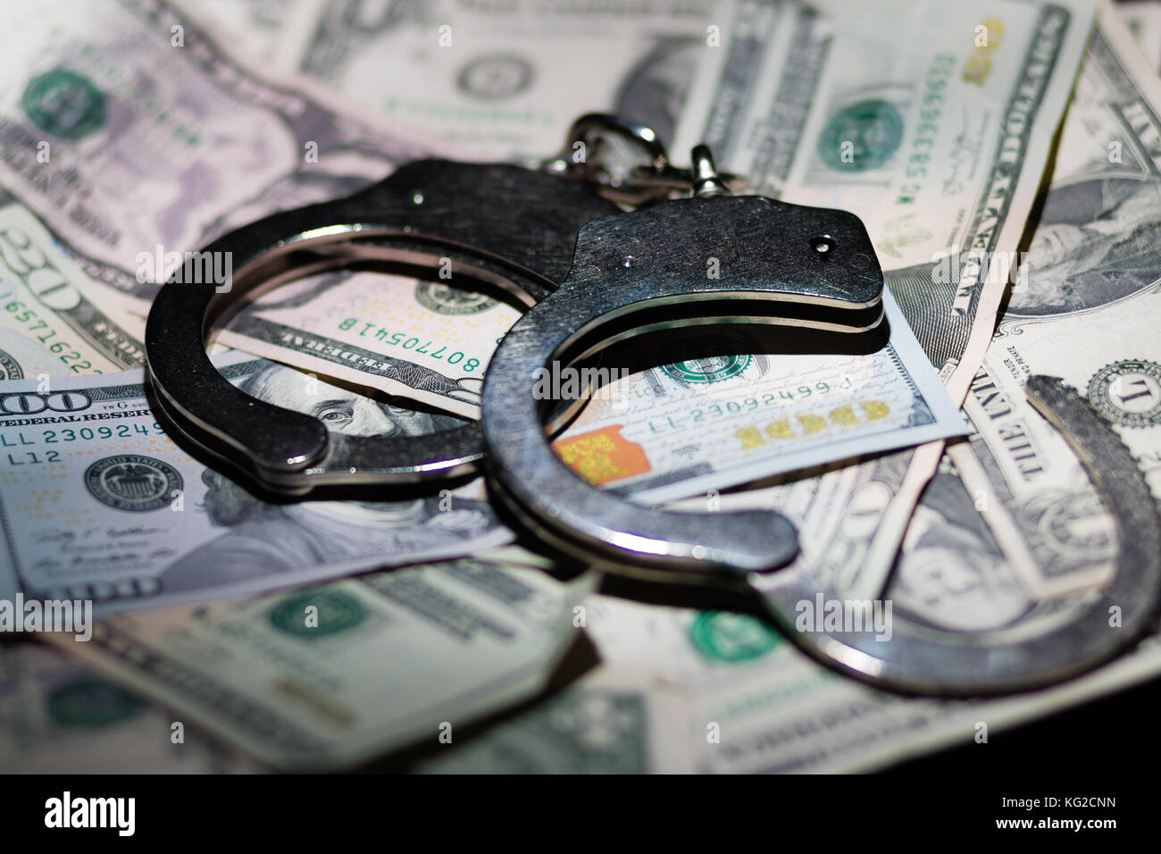 A pair of open handcuffs on a pile of American Dollars. Stock Photo