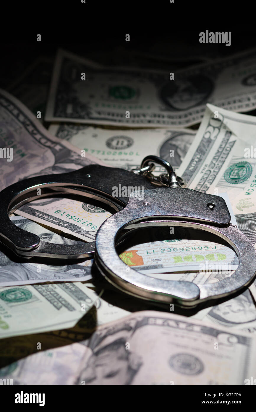 A pair of closed handcuffs on a pile of American Dollars Stock Photo