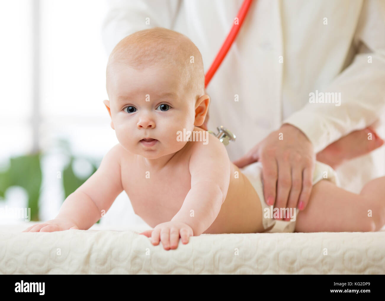 Pediatrician doctor examines baby with stethoscope checking heart beat
