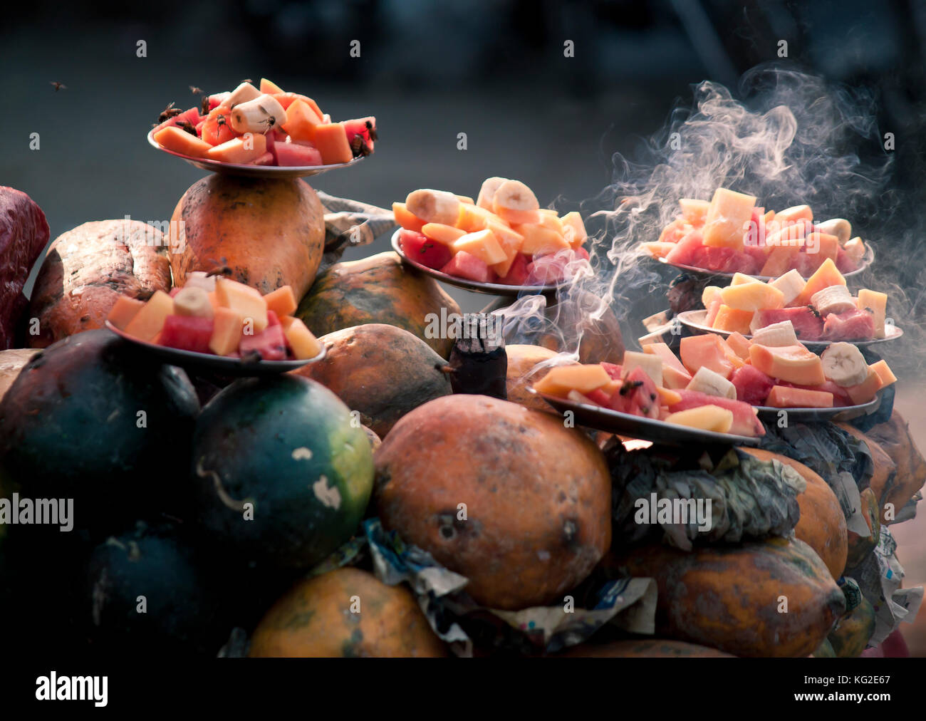 Incense smoke used to keep insects away from fresh fruit portions on display at market Stock