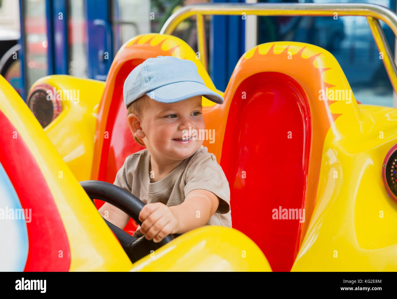 Little baby boy riding car in amusement park Stock Photo