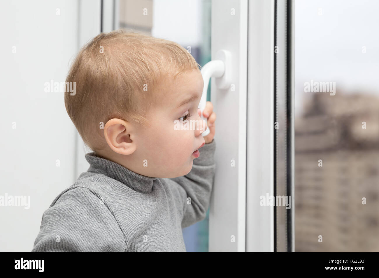 Little baby kid looking out the window Stock Photo