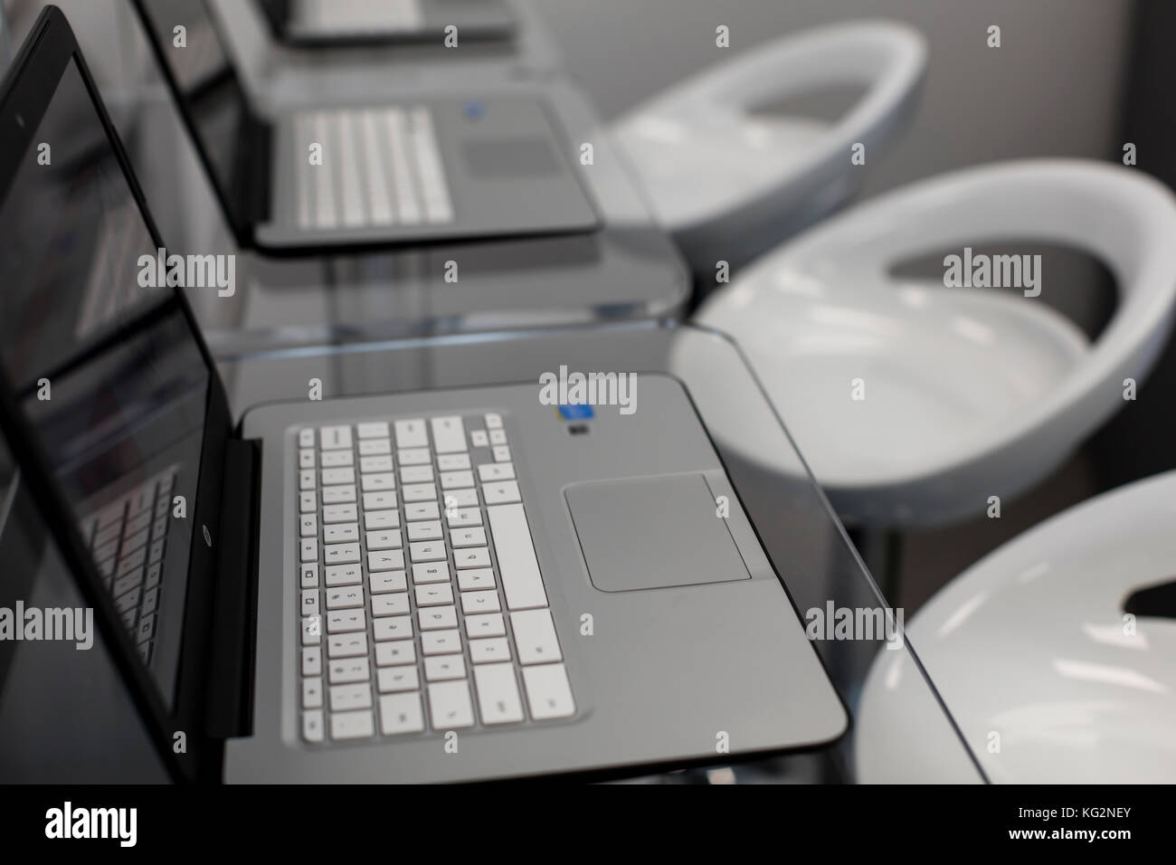 New, open laptops, on a glass desktop; modern white chairs in