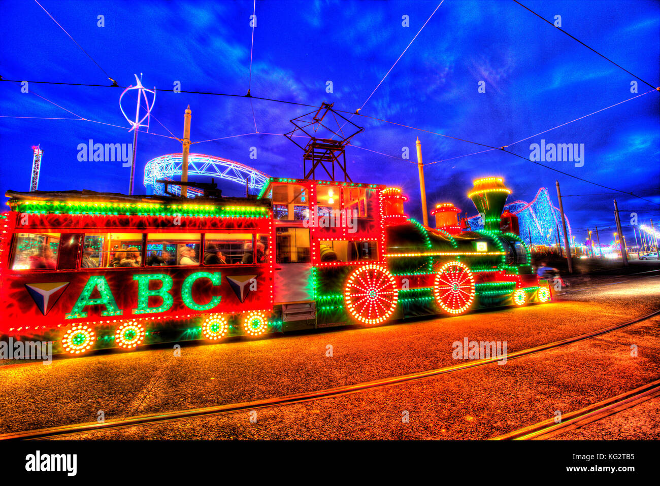 Town of Blackpool, England. Artistic night view of the illuminated trams, during the Blackpool Illumination festivities, with Blackpool Pleasure Beach Stock Photo